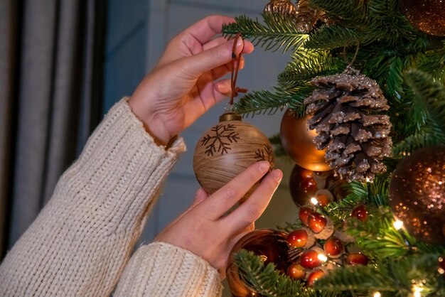 Een vrouw versiert een kerstboom met een houten ornament