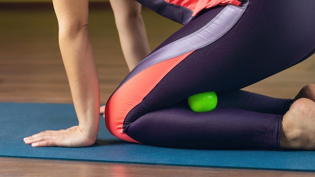 Een vrouw voert myofasciale ontspanning uit van superflexibele beenspieren met een massagebal