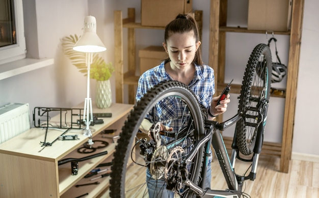 Een vrouw voert onderhoud uit aan zijn mountainbike. Concept van het repareren en voorbereiden van de fiets voor het nieuwe seizoen