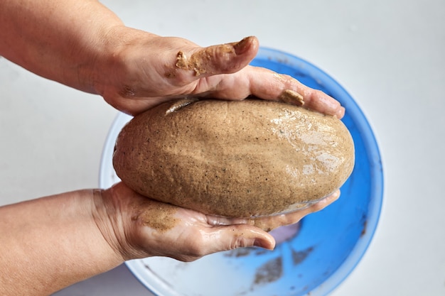Een vrouw vormt een zelfgebakken brood om daarna te bakken