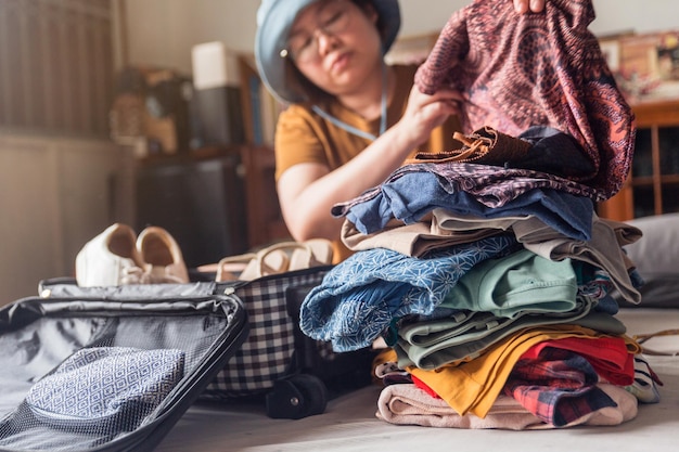 Een vrouw vouwt kleding van een stapel geselecteerde spullen en stopt ze in bagage.