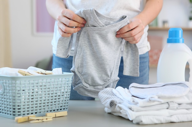 Een vrouw vouwt schone en frisse babykleertjes en wast babykleertjes