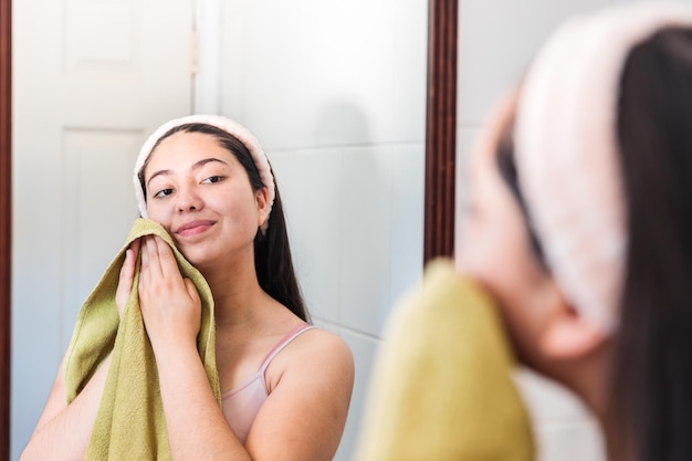 Een vrouw wast haar gezicht voor een spiegel