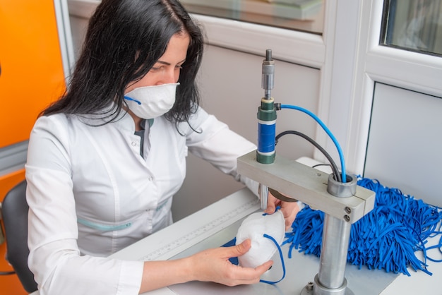 Een vrouw werkt aan een machine voor de vervaardiging van medische maskers met nanovezel en soldeerlussen met echografie.