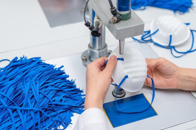 Een vrouw werkt in een fabriek voor de vervaardiging van medische maskers met nanovezels en soldeerlussen met echografie op een machine Coronavirus en Covid19 Protection Closeup