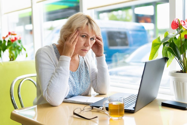 Een vrouw werkt met een laptop aan een tafel in de kamer