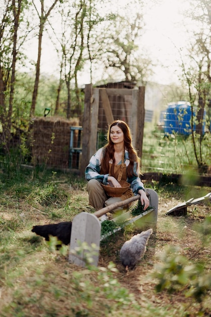 Een vrouw werkt op een boerderij en voedt haar kippen met gezond voedsel door jong biologisch gras in hun voeders te zetten om ze te voeden. Hoogwaardige foto