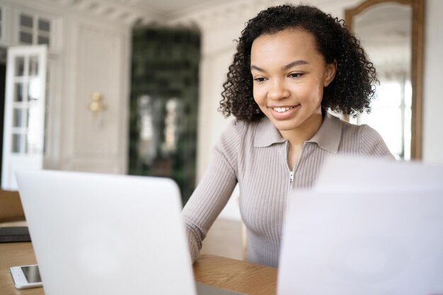 Een vrouw werkt op kantoor aan een nieuw project in een financieel bedrijf en gebruikt een laptop op het bureau en een telefoon