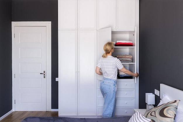 Een vrouw zet orde op zaken in een witte kast met kopieerpasta voor kleding