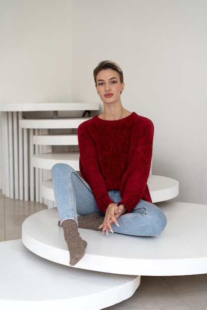 Een vrouw zit aan een ronde tafel in een huis met een witte trap.