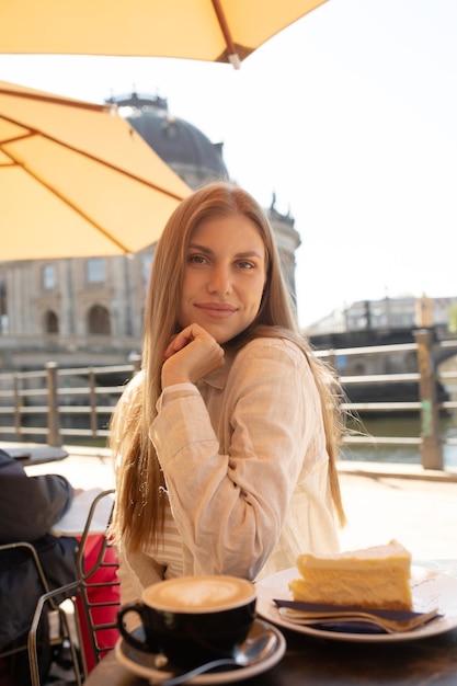 Een vrouw zit aan een tafel met een gele paraplu boven haar hoofd.