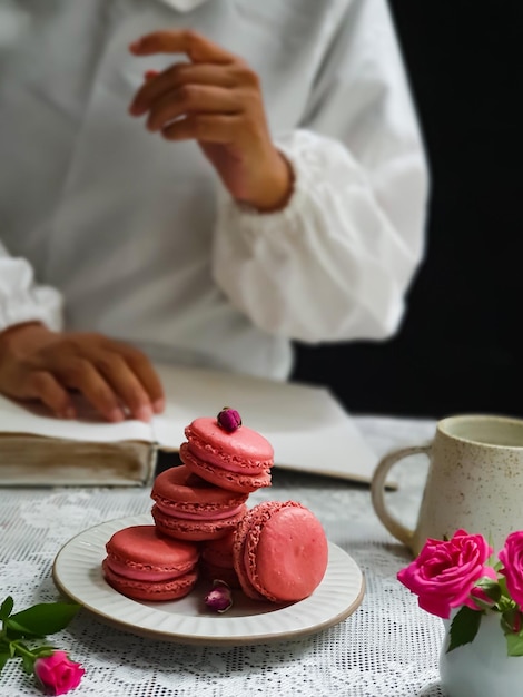 Een vrouw zit aan een tafel met een stapel bitterkoekjes en een boek.