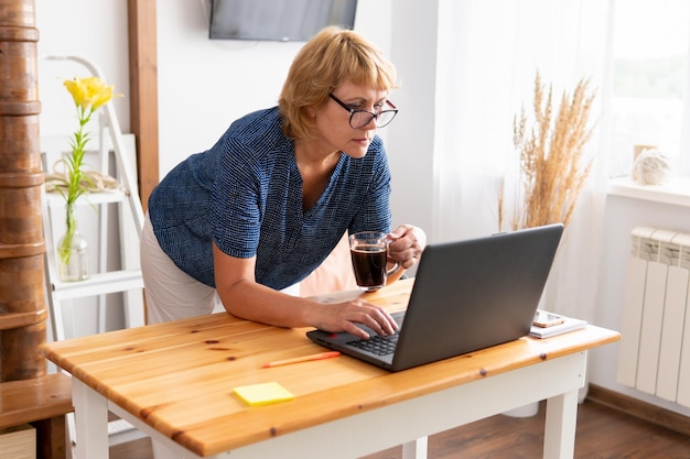 Een vrouw zit in een kamer aan een tafel met een laptop