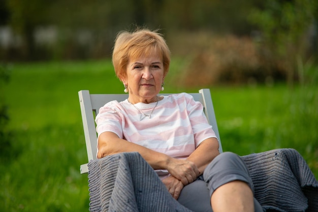 Een vrouw zit in een stoel in een stadspark