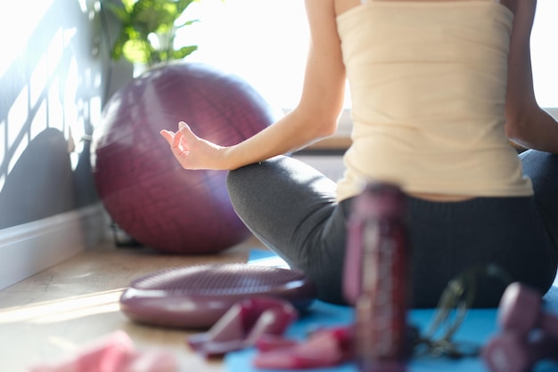 Een vrouw zit op de grond in een yogahouding van achteren