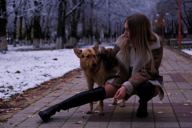 een vrouw zit op een bankje met een hond