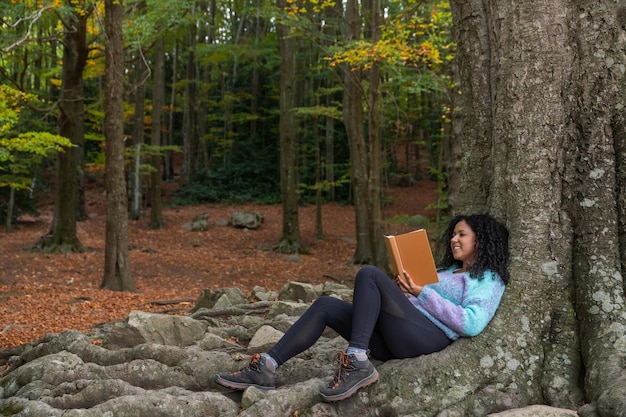 Een vrouw zit op een boomstam een boek te lezen.