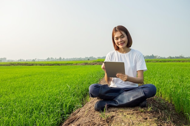 Een vrouw zit op het gras in een park met een laptop en geniet van de natuur en technologie buiten