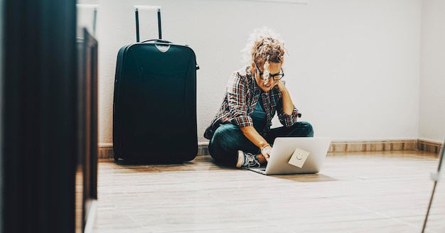 Een vrouw zittend op de vloer in een leeg huis appartement met laptopcomputer concept van nieuw huis en verhuizen na hypothecaire lening vastgoed koper plan en ontwerp platte meubels en stijl