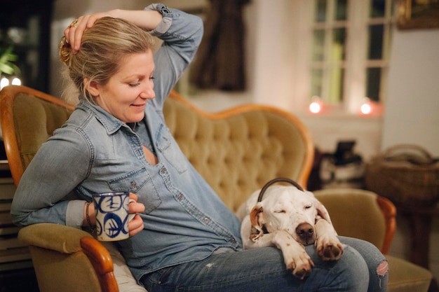 Een vrouw zittend op een bank met een grote dop met zijn hoofd op haar schoot