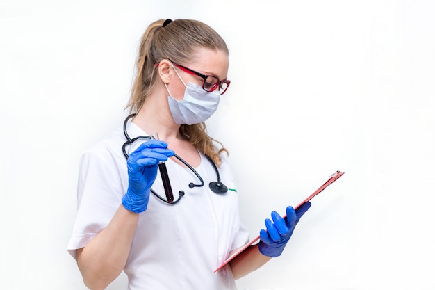 Een vrouwelijke arts in een beschermend masker met een reageerbuis in haar handen op wit