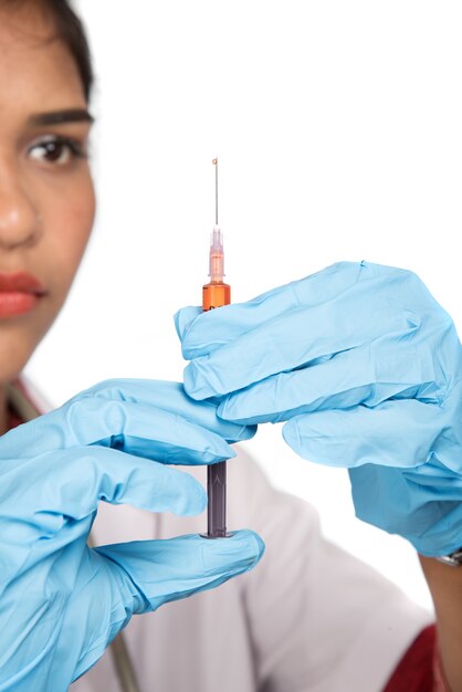 Een vrouwelijke arts met een stethoscoop houdt een injectie of spuit.