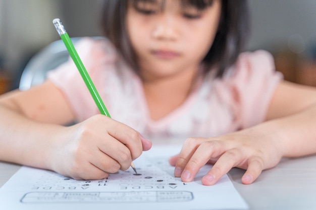 Een vrouwelijke aziatische studente concentreert zich op het examenpapier in de klas