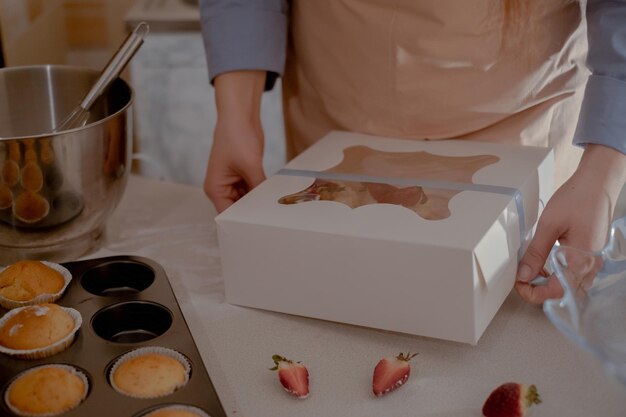 Foto een vrouwelijke banketbakker verpakt cupcakes in verpakkingen voor verzending aan klanten die zelfgemaakte producten tentoonstellen