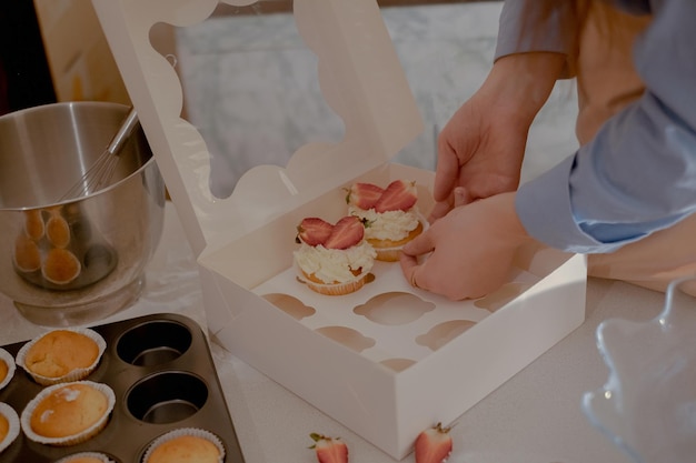 Een vrouwelijke banketbakker verpakt cupcakes in verpakkingen voor verzending aan klanten