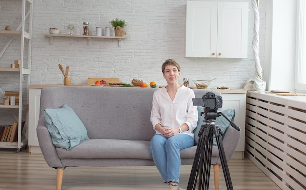 Een vrouwelijke blogger zit op de bank voor een videocamera die uitzendt voor haar kijkers