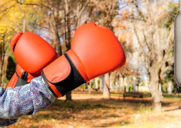 Een vrouwelijke bokshandschoenen boksen in profiel in een park Authentiek kickboksen