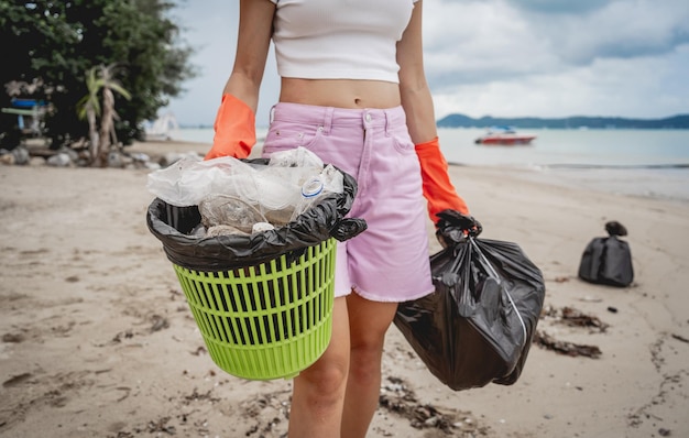 Een vrouwelijke ecoloog-vrijwilliger maakt het strand aan de kust schoon van plastic en ander afval