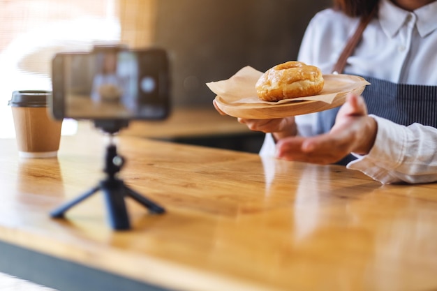 Een vrouwelijke foodblogger of vlogger die een stukje donut laat zien terwijl ze een video op camera opneemt