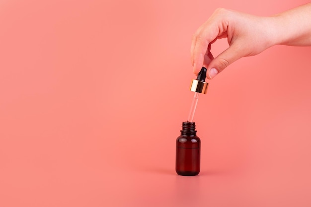 Een vrouwelijke hand houdt een cosmetisch serum met druppelaar vast Natuurlijk cosmetisch product voor zuiverheid en hydratatie van de huid