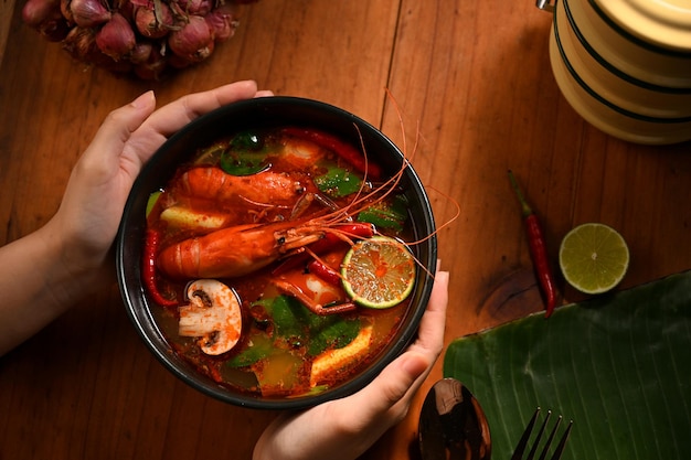 Een vrouwelijke handen die een kom Tom Yam Kung . serveert