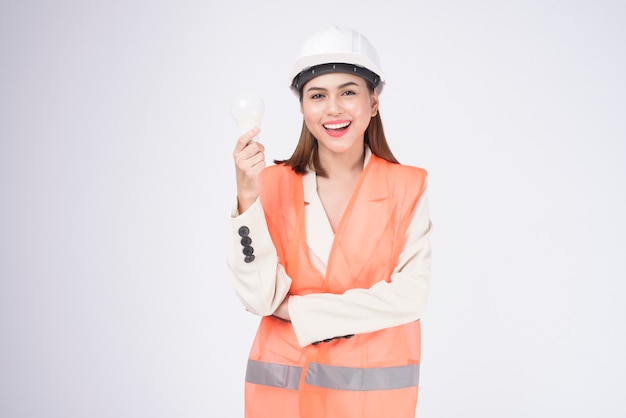 Een vrouwelijke ingenieur die een beschermende helm draagt over een witte achtergrondgeluidsstudio