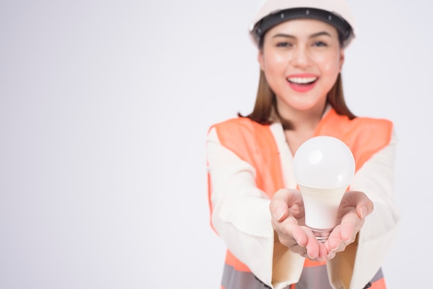 Een vrouwelijke ingenieur die een beschermende helm draagt over een witte achtergrondgeluidsstudio