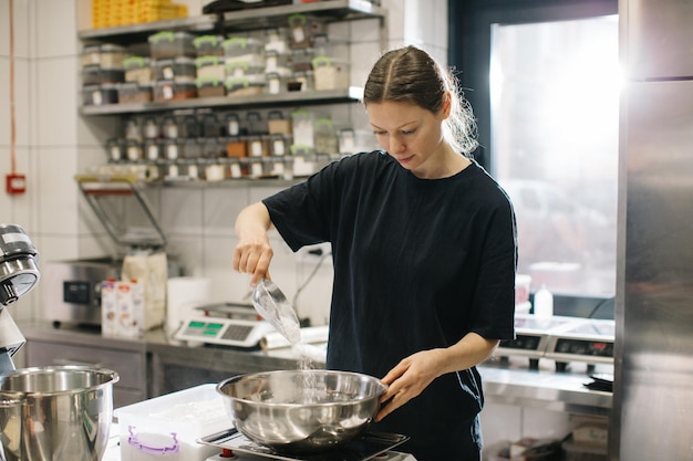 Een vrouwelijke kok werkt in een moderne industriële keuken Het proces van het maken van taarten in een bakkerij of café