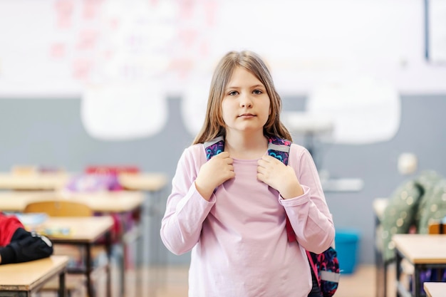 Een vrouwelijke leerling met schooltas die zich in een klaslokaal bevindt