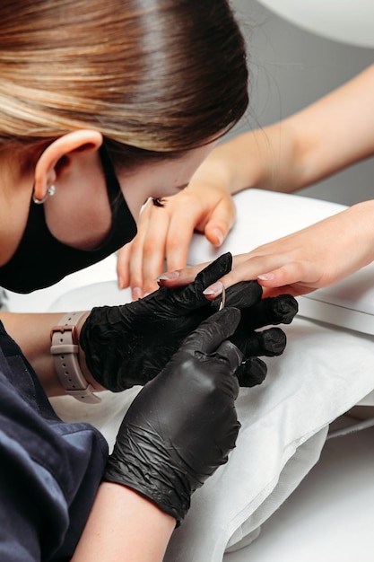 Foto een vrouwelijke nagelsalonmeester snijdt de nagelriem af langs de rand van de nagelplaat op haar vingers