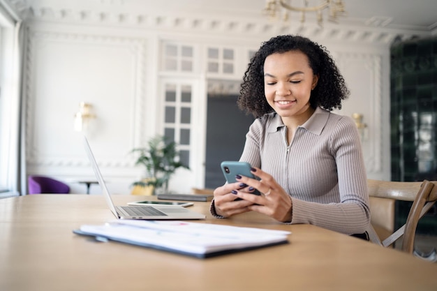 Een vrouwelijke ontwerper werkt op kantoor aan een nieuw project in een financieel bedrijf met een laptop op het bureau en een telefoon