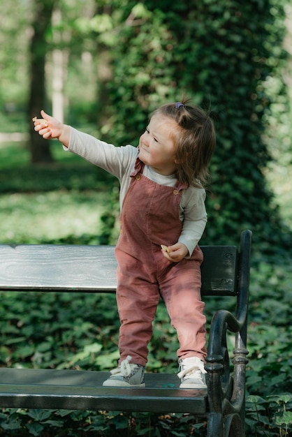 Foto een vrouwelijke peuter zit op de tuinbank in het park