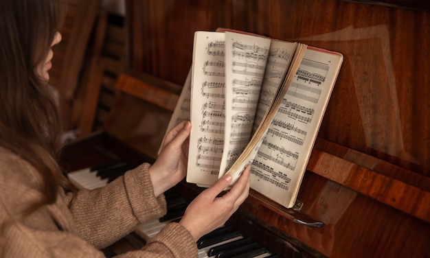 Een vrouwelijke pianist zit aan de piano door de noten te bladeren.