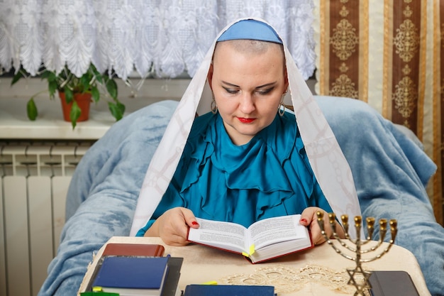 Een vrouwelijke rabbijn van de Reform Judaism-gemeenschap kaal geschoren in een keppeltje bidt aan tafel voor een siddur Horizontale foto