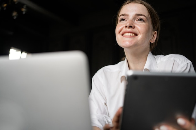 Een vrouwelijke receptioniste in het hotel gebruikt een laptop om per post met een klant te communiceren