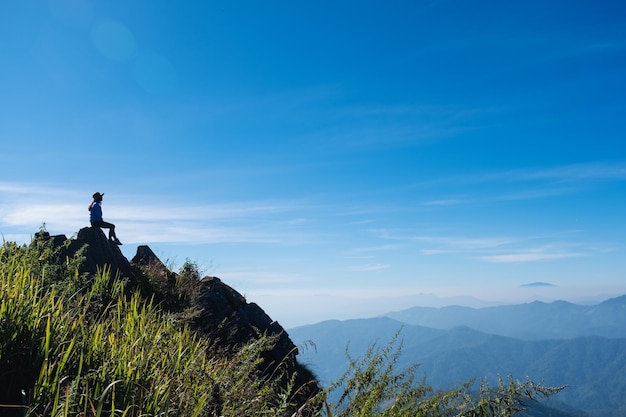 Een vrouwelijke reiziger die op de bergtop wandelt en zit en naar een prachtig uitzicht kijkt