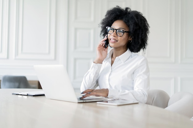 Een vrouwelijke secretaresse met een bril werkt op kantoor en beantwoordt de post van de klant met een laptop