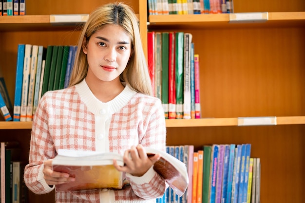 Een vrouwelijke student leest een boek in de universiteitsbibliotheek