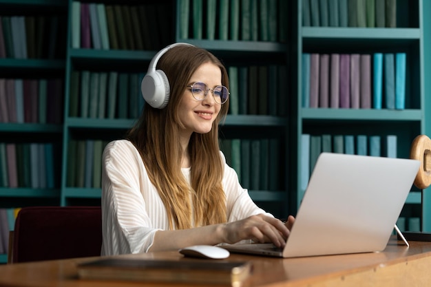 Foto een vrouwelijke student met een bril werkt in een modern kantoor en gebruikt een coworking-ruimte op een laptopcomputer
