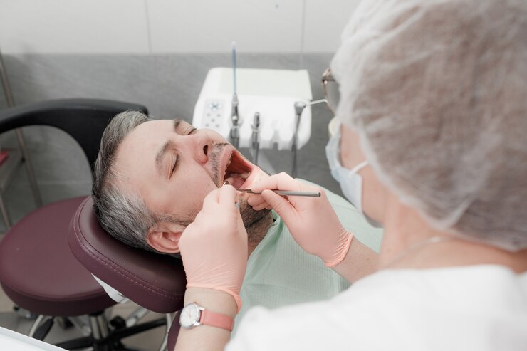 Een vrouwelijke tandarts behandelt de tanden van een mannelijke patiënt in het kantoor van een tandheelkundige kliniek